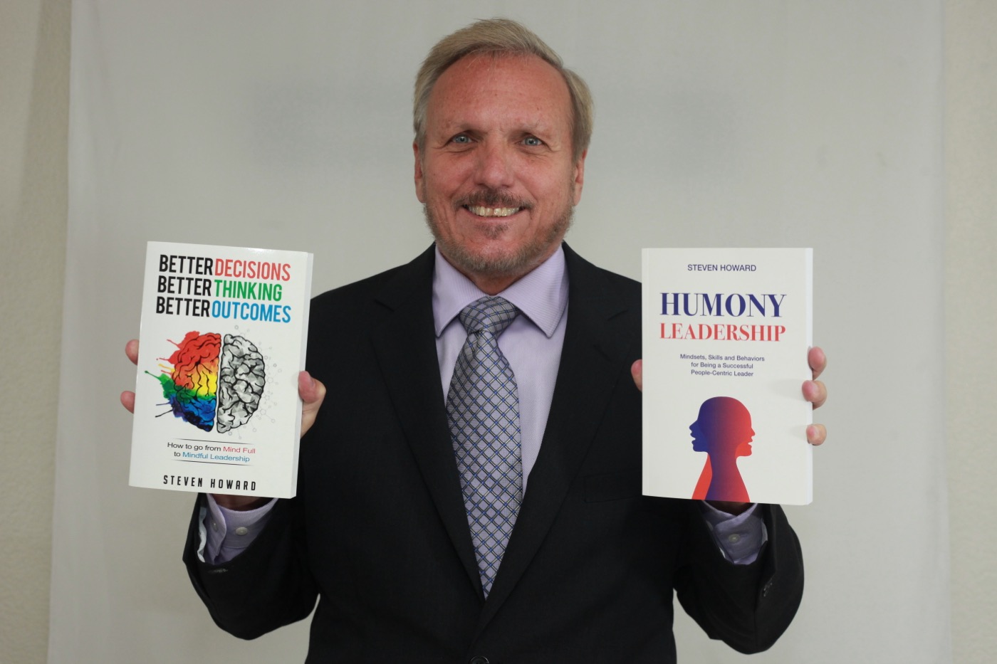 Steven Howard holding two of his books, Better Decisions. Better Thinking. Better Outcomes. and Humony Leadership